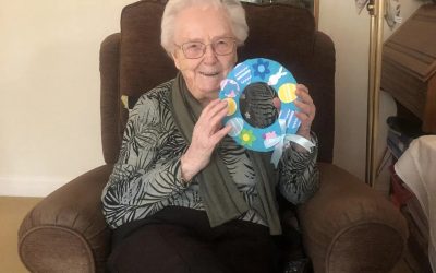 Mrs Evans from Wilmslow showing her carer a beautiful Easter wreath she has made