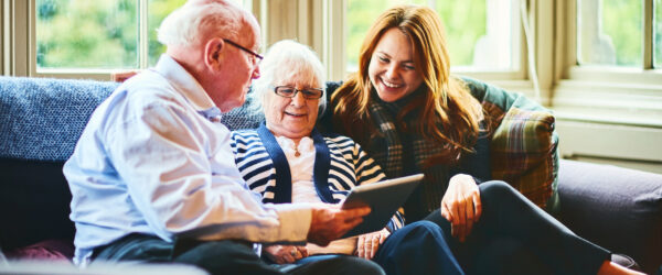 Senior couple with carer using tablet