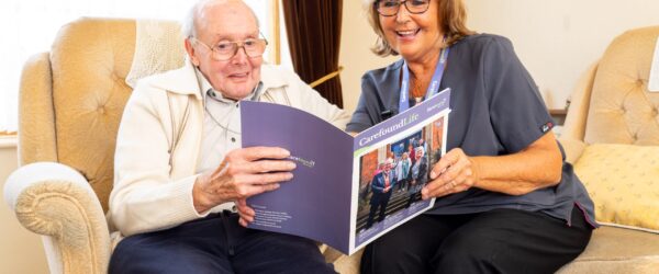 Carer and elderly man reading CarefoundLife