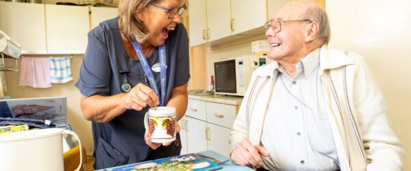 Carer laughing in kitchen with older gentleman