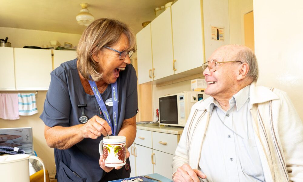 Carer laughing in kitchen with older gentleman