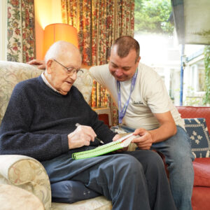 elderly-man-with-carer-doing-corssword